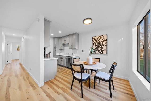 kitchen with gray cabinets, light countertops, stainless steel dishwasher, and a healthy amount of sunlight