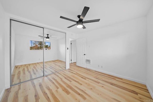 unfurnished bedroom featuring light wood finished floors, baseboards, visible vents, a ceiling fan, and a closet