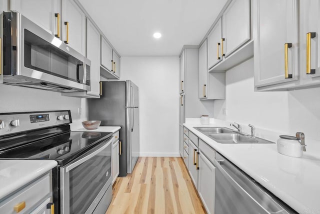 kitchen featuring stainless steel appliances, light countertops, light wood-style floors, a sink, and recessed lighting