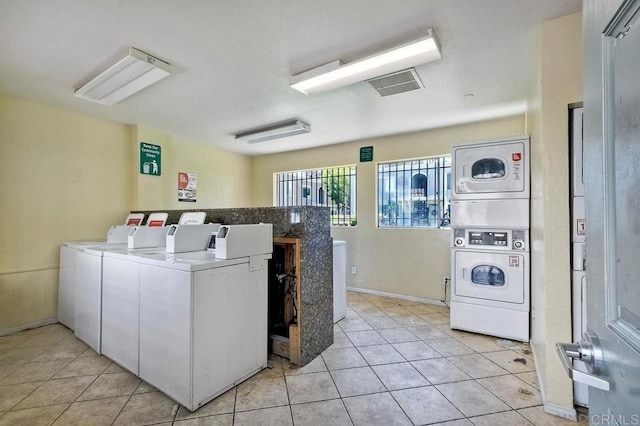 community laundry room with stacked washer / dryer, light tile patterned flooring, washer and clothes dryer, and visible vents