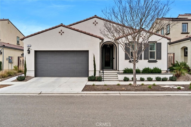 mediterranean / spanish home featuring driveway, a tiled roof, a garage, and stucco siding