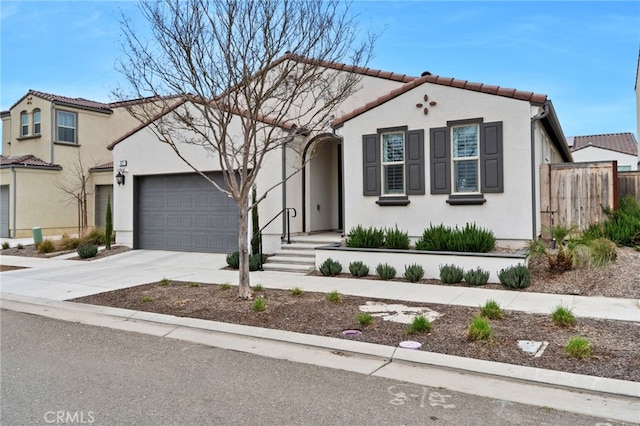 view of front of house featuring driveway, a tile roof, an attached garage, fence, and stucco siding