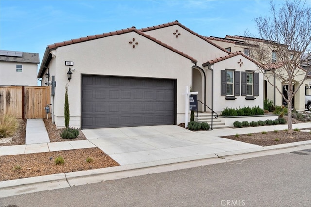 mediterranean / spanish house with a tile roof, driveway, an attached garage, and stucco siding