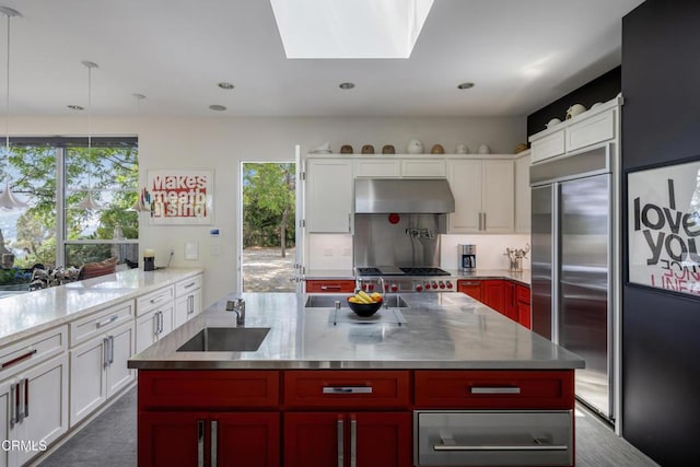 kitchen with under cabinet range hood, high quality fridge, a sink, and white cabinets