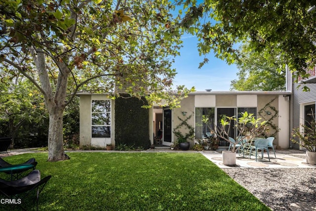 view of front of property with a front yard, a patio, and stucco siding