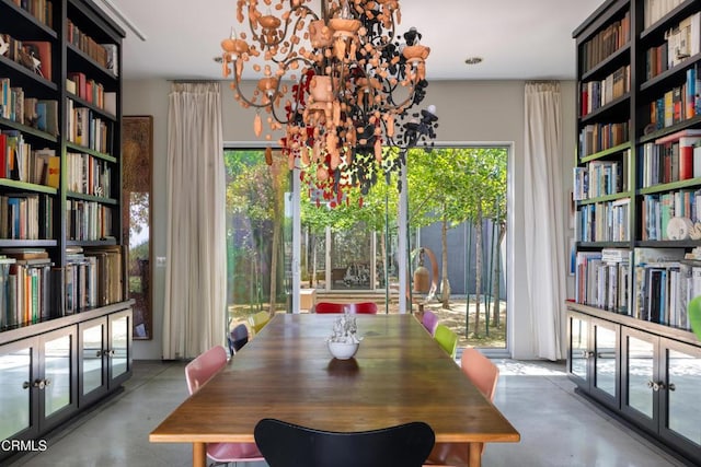 dining room with a wealth of natural light, a chandelier, and concrete flooring