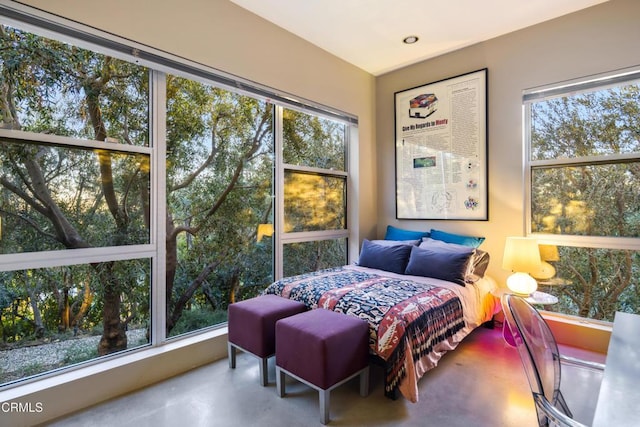 bedroom with concrete flooring and multiple windows