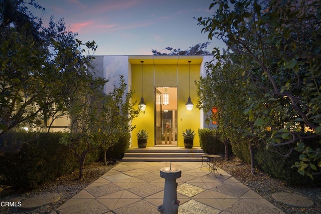 exterior entry at dusk featuring stucco siding