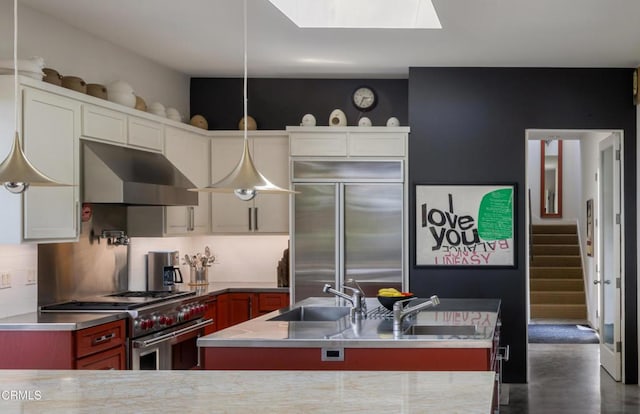 kitchen featuring a center island with sink, high end appliances, backsplash, a sink, and under cabinet range hood