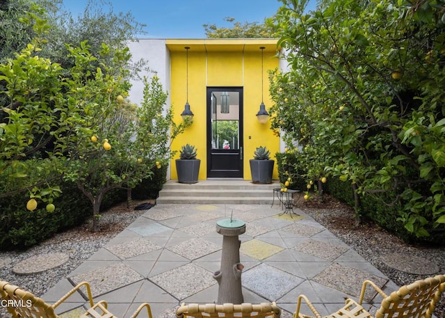 view of exterior entry featuring a patio area and stucco siding