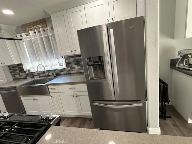 kitchen with appliances with stainless steel finishes, white cabinetry, a sink, and decorative backsplash