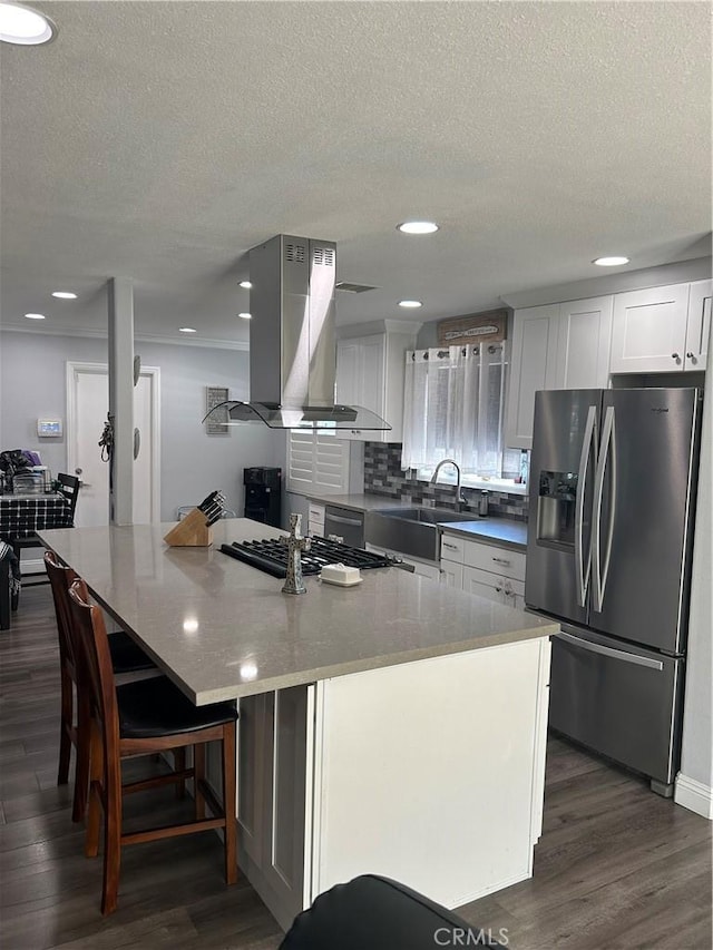 kitchen with island range hood, white cabinets, appliances with stainless steel finishes, a center island, and a sink