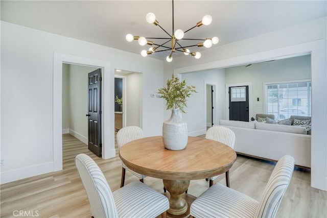 dining room featuring light wood-style floors, baseboards, and an inviting chandelier