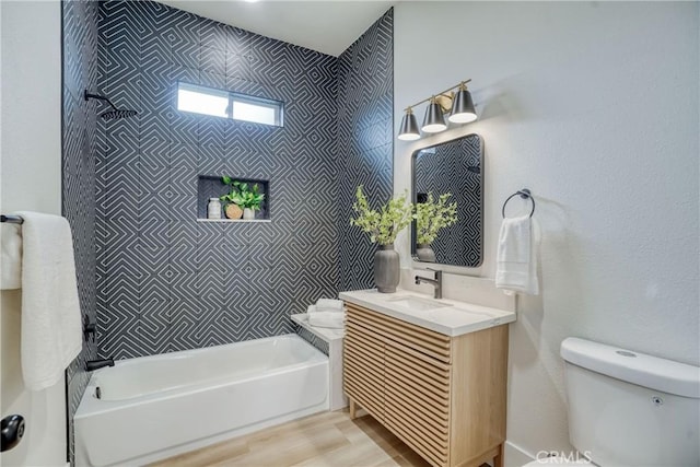 bathroom with toilet, shower / washtub combination, wood finished floors, and vanity