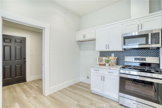 kitchen featuring white cabinets, light wood-type flooring, tasteful backsplash, and stainless steel appliances