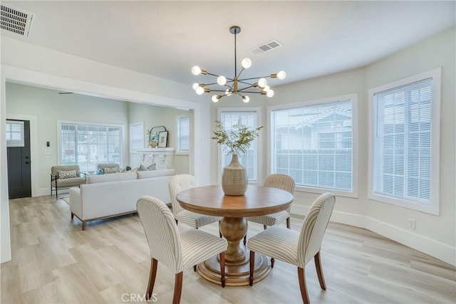 dining space featuring an inviting chandelier, light wood-style flooring, and visible vents