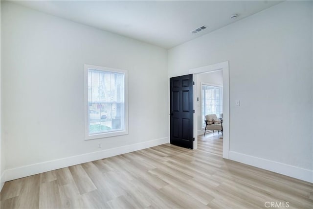 empty room featuring baseboards, visible vents, and light wood finished floors