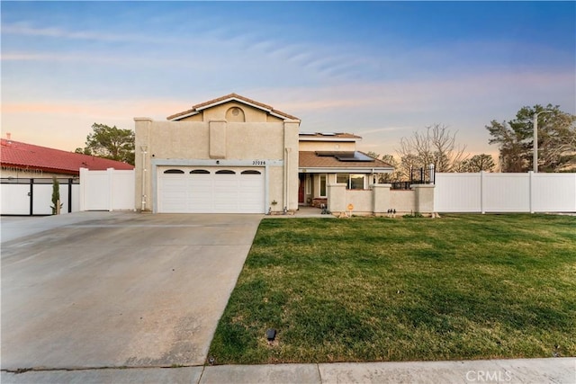 view of front of house featuring a yard, concrete driveway, fence, and stucco siding