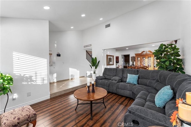 living area with high vaulted ceiling, recessed lighting, dark wood-style flooring, visible vents, and stairs