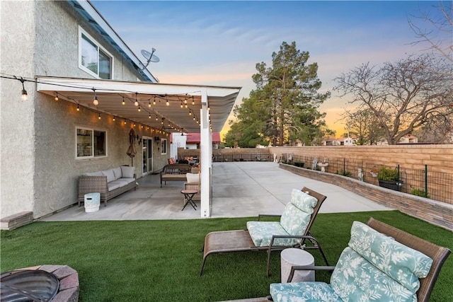 patio terrace at dusk with an outdoor living space with a fire pit, a yard, and a fenced backyard