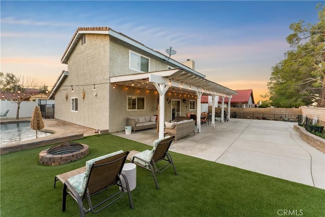 rear view of property featuring an outdoor living space with a fire pit, a patio, stucco siding, a lawn, and a fenced backyard