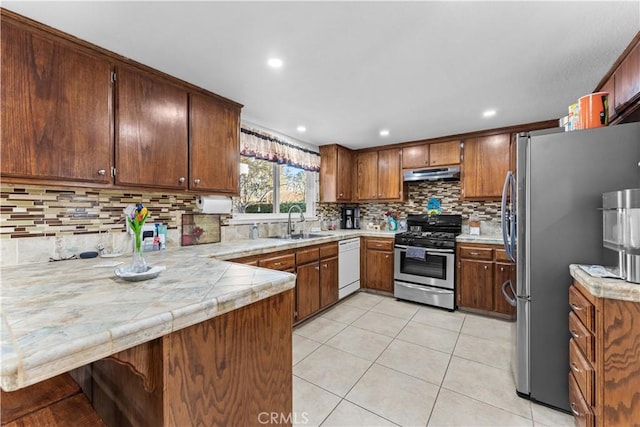 kitchen with light tile patterned floors, appliances with stainless steel finishes, a sink, a peninsula, and under cabinet range hood