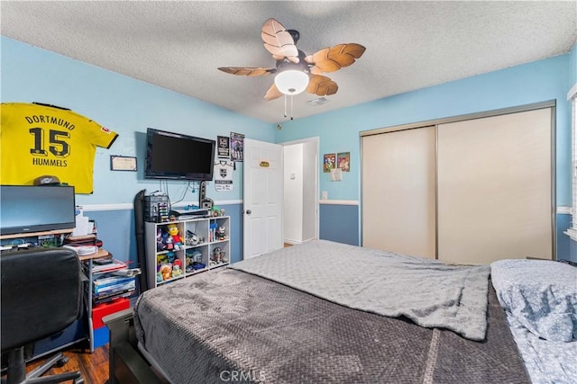 bedroom featuring a ceiling fan, a closet, a textured ceiling, and wood finished floors