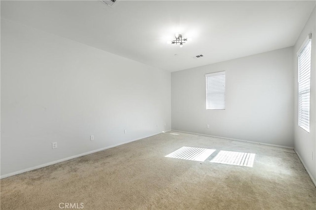 spare room featuring light carpet and visible vents