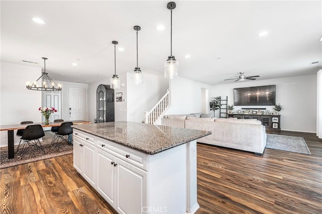 kitchen featuring white cabinetry, open floor plan, dark stone counters, dark wood finished floors, and pendant lighting