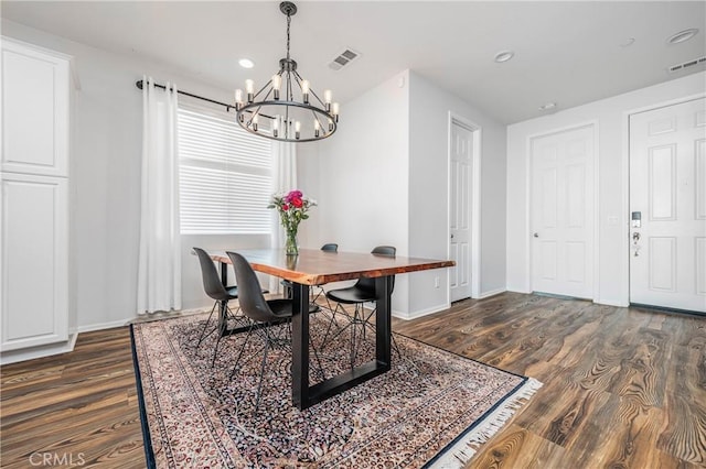 dining space with dark wood-style floors, baseboards, visible vents, and an inviting chandelier