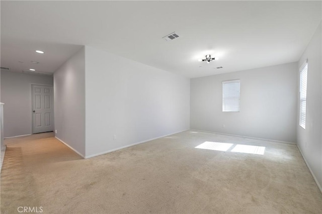 empty room featuring visible vents, light carpet, and baseboards