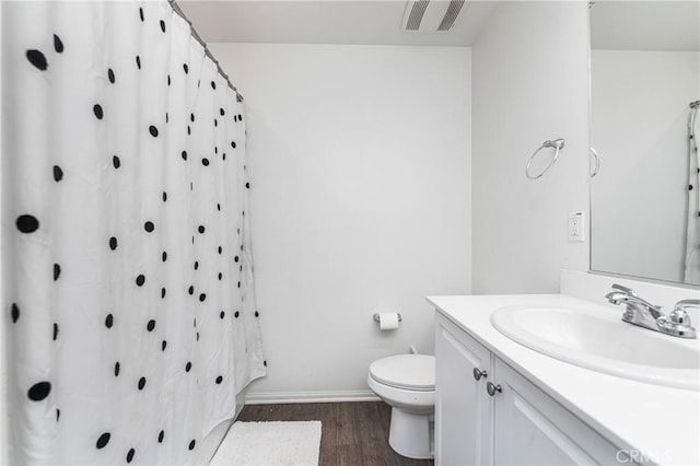 bathroom with visible vents, toilet, vanity, wood finished floors, and baseboards