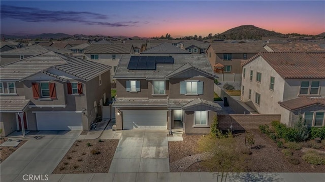 view of property with roof mounted solar panels, a residential view, concrete driveway, and stucco siding