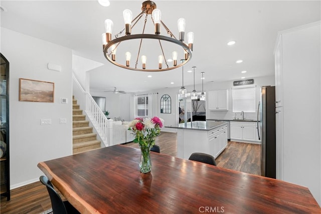 dining room featuring ceiling fan with notable chandelier, stairway, dark wood finished floors, and recessed lighting