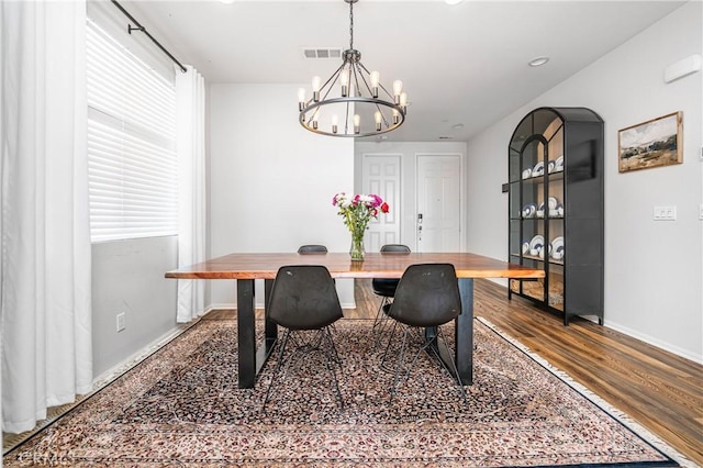 dining room with arched walkways, a notable chandelier, visible vents, wood finished floors, and baseboards