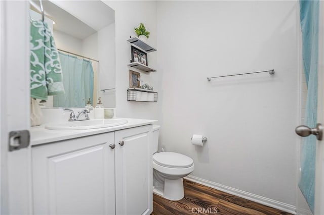 bathroom featuring baseboards, a shower with shower curtain, toilet, wood finished floors, and vanity