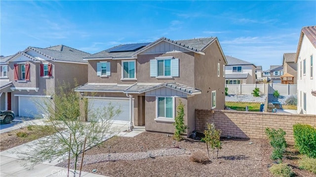 view of front of house featuring stucco siding, solar panels, fence, a residential view, and driveway