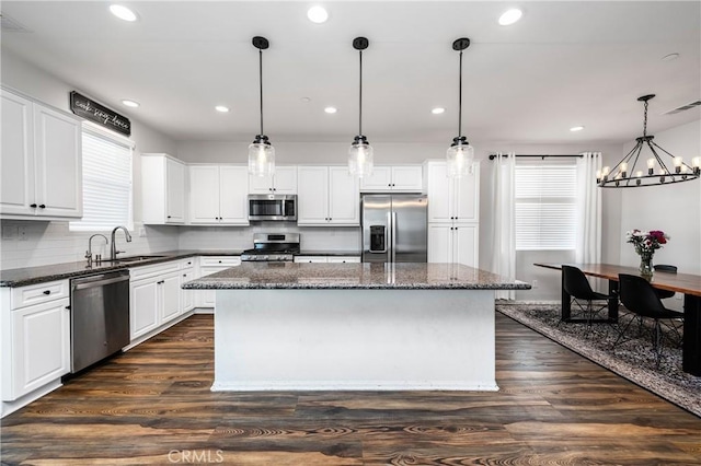 kitchen featuring stainless steel appliances, a center island, white cabinets, and decorative light fixtures