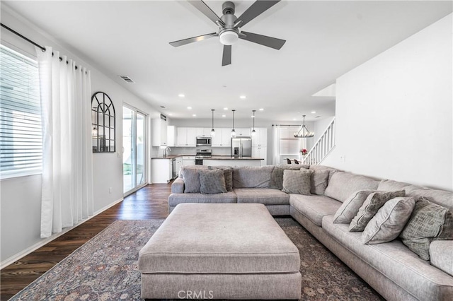 living room with baseboards, visible vents, dark wood-type flooring, ceiling fan with notable chandelier, and recessed lighting