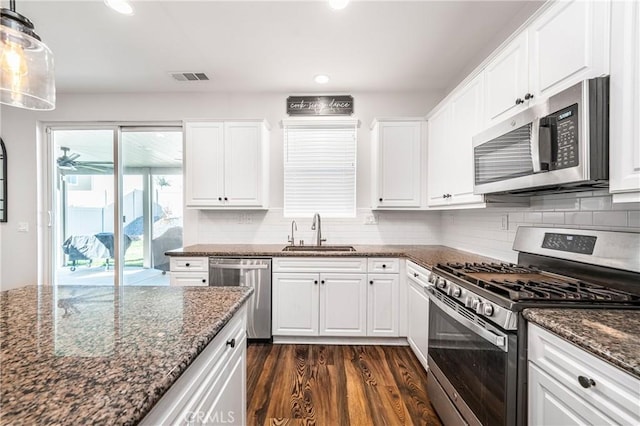 kitchen with white cabinets, stainless steel appliances, a sink, and decorative light fixtures