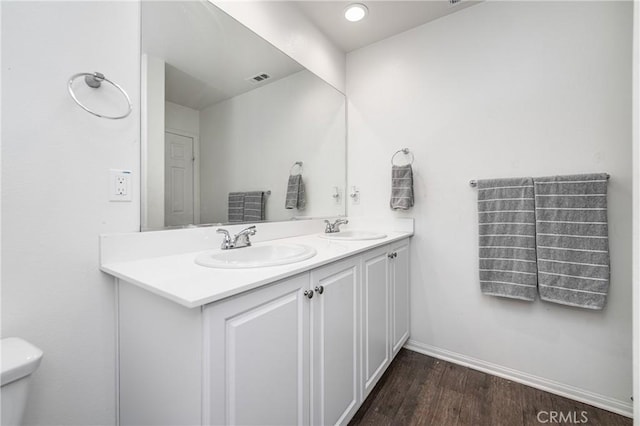 bathroom with wood finished floors, visible vents, a sink, and double vanity