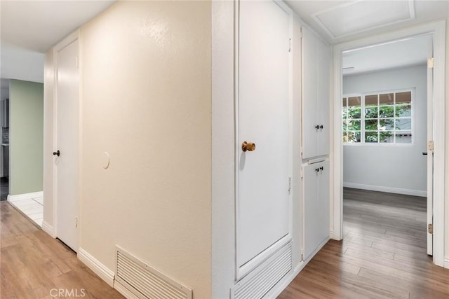 hall featuring attic access, light wood-style floors, and baseboards
