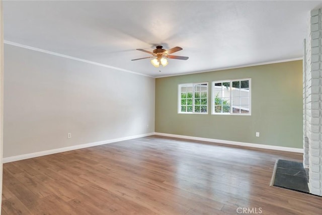 spare room featuring ceiling fan, crown molding, wood finished floors, and baseboards