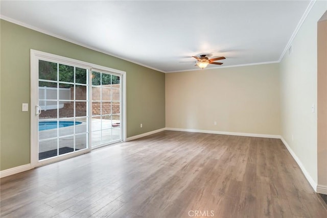 empty room featuring crown molding, ceiling fan, wood finished floors, and baseboards