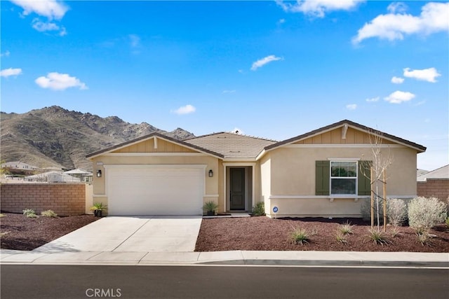 ranch-style house featuring stucco siding, fence, a mountain view, a garage, and driveway