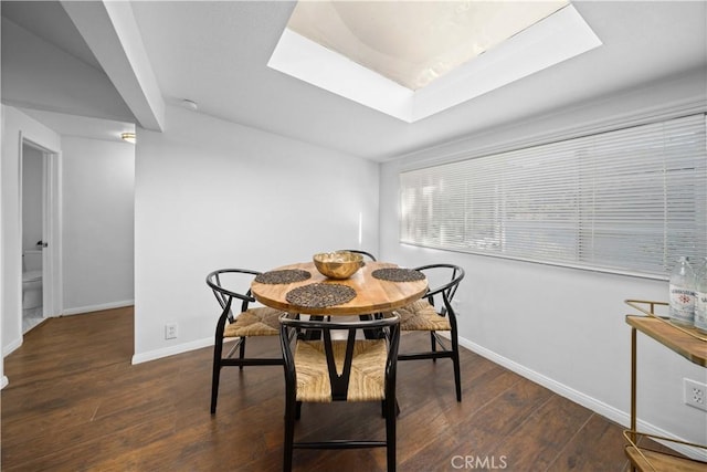 dining space featuring dark wood-style floors, a skylight, and baseboards