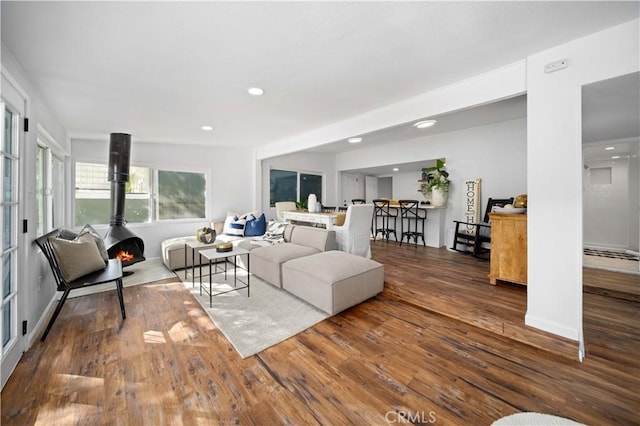 living area with a wood stove, wood finished floors, and recessed lighting