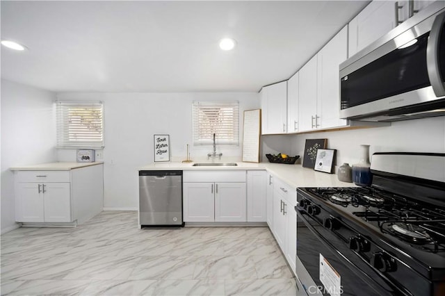 kitchen featuring white cabinetry, stainless steel appliances, a sink, and light countertops