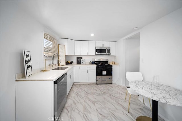 kitchen featuring white cabinets, marble finish floor, stainless steel appliances, light countertops, and a sink