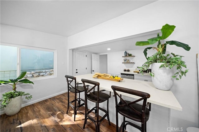 kitchen with a kitchen breakfast bar, baseboards, light countertops, dark wood-style floors, and open shelves